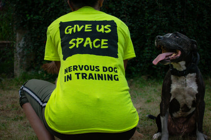 lady-crouched-in-high-vis-nervy-mutt-give-us-space-tshirt-facing-away-next-to-smiling-dog