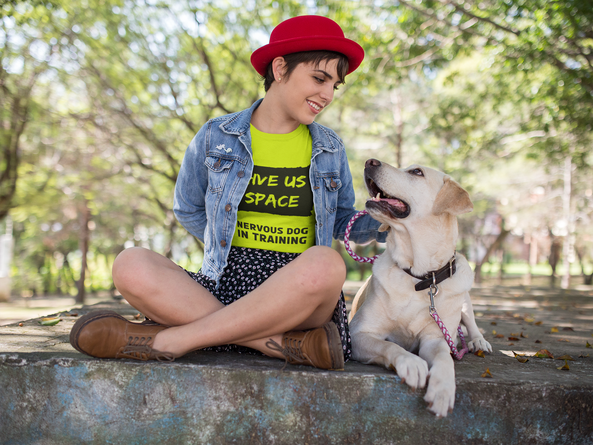 woman-in-red-hat-wearing-denim-jacket-and-bright-yellow-nervy-mutt-tshirt-looking-down-at-her-nervous-labrador